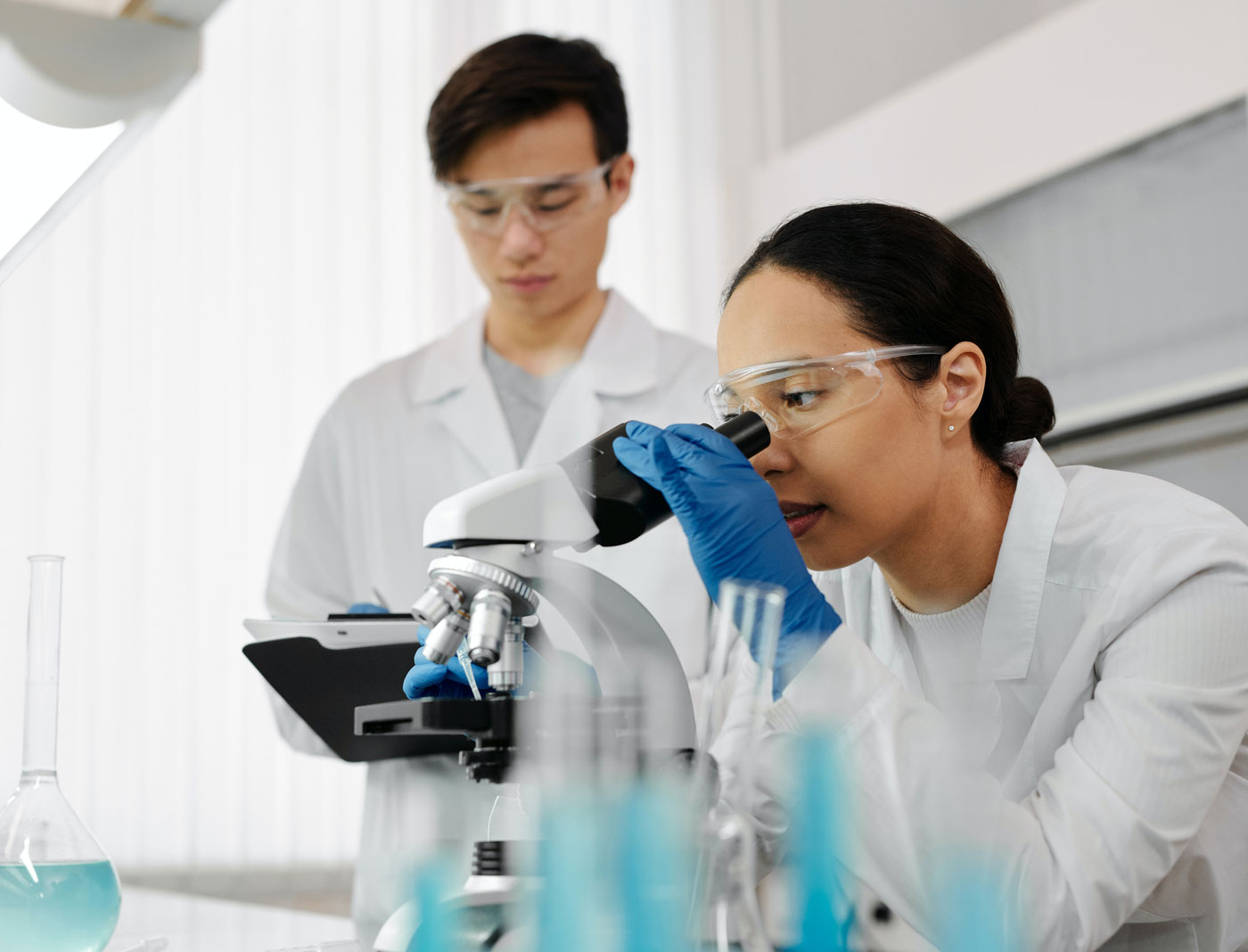 Two food scientists looking into a microscope and performing lab tests