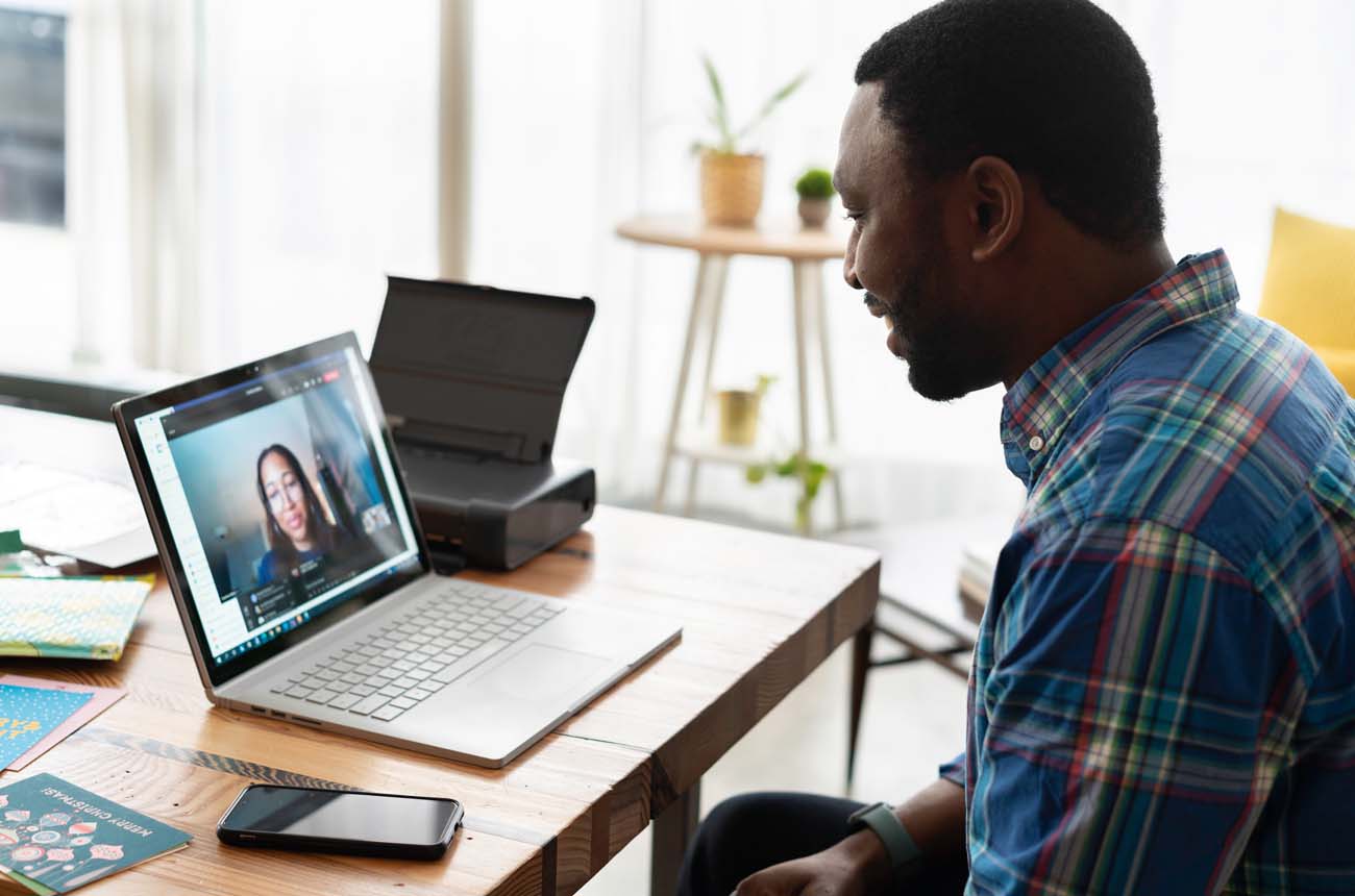 Man at desk on his laptop speaking on a video call.