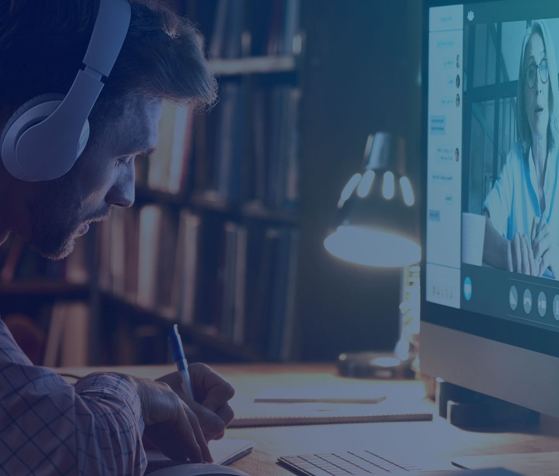 Man wearing headphones taking notes and watching a live virtual class