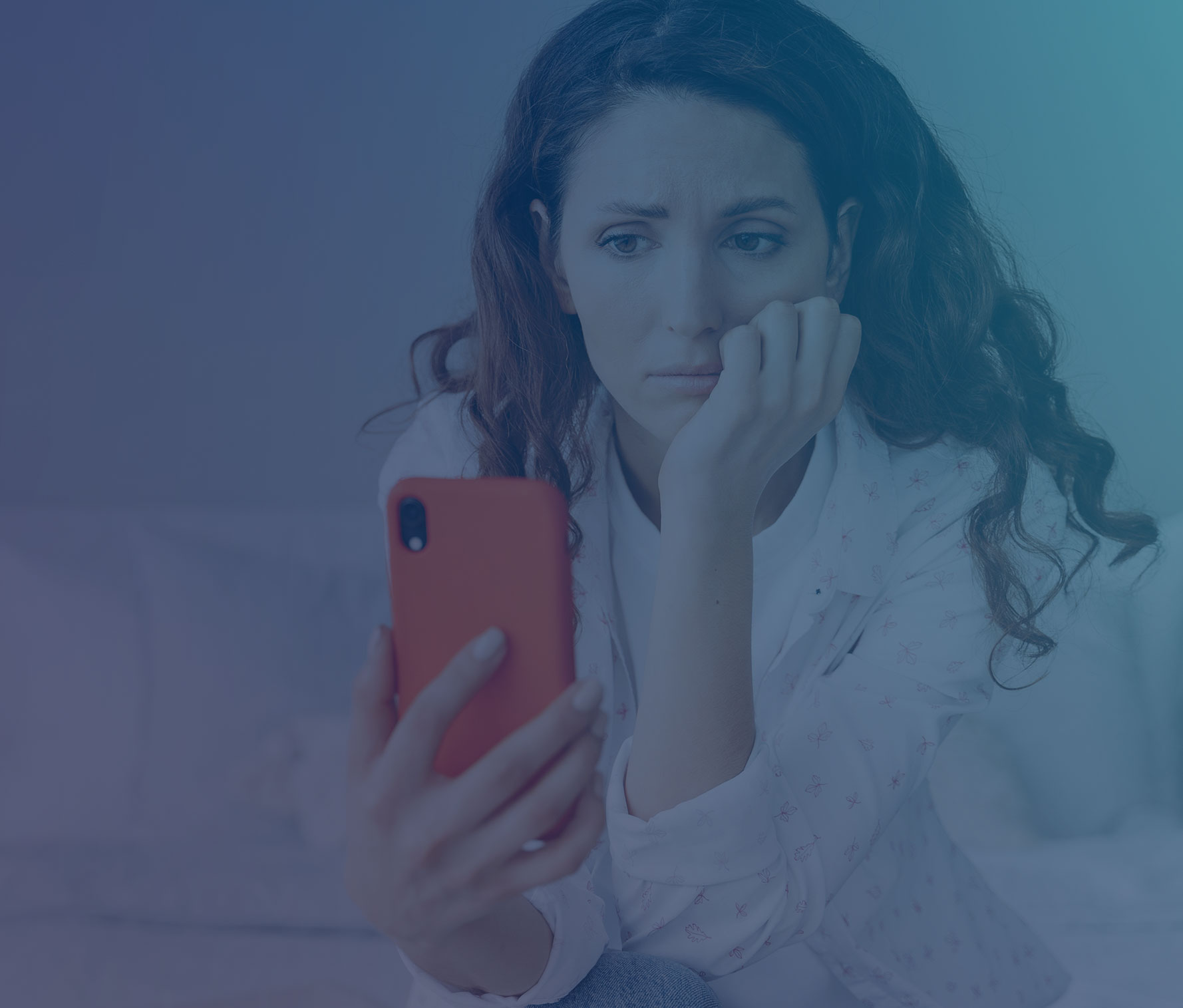 Young woman in casual attire looking anxious while doom scrolling on orange phone, sitting on bed in minimalist bedroom
